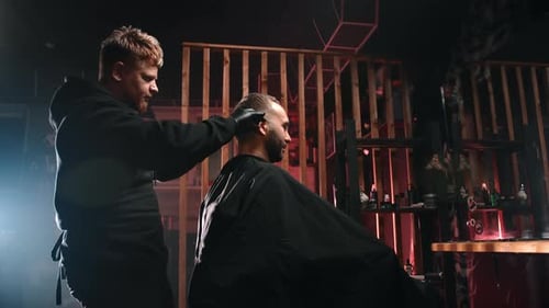 Man Getting Haircut by Barber in Darkly Lit Room