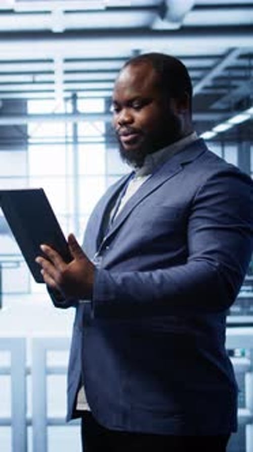 Man in Server Room Holding Tablet