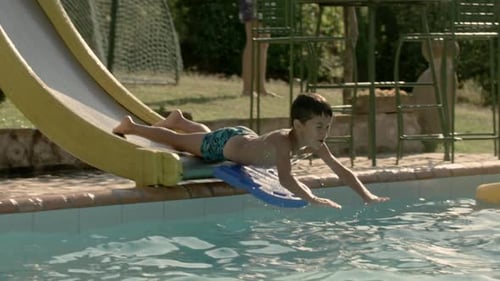 Caucasian child diving face down a slide into the pool in slow motion