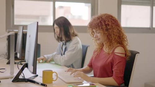 Femme aux cheveux bouclés travaillant de manière concentrée à côté d'un partenaire