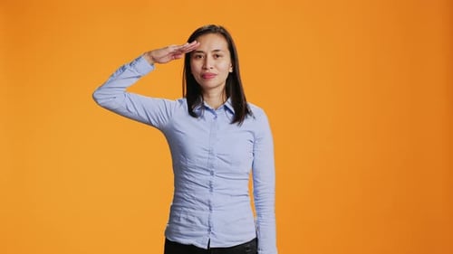 Woman Smiles and Salutes in Studio Setting