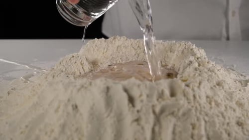 Water Pouring Into Flour for Dough Preparation