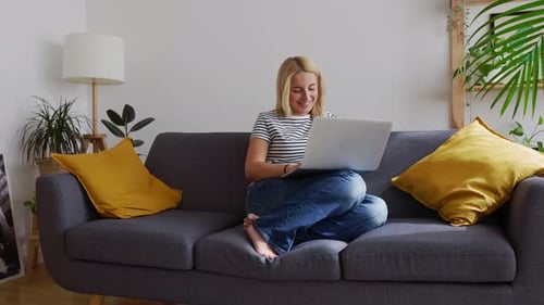 Woman Using Laptop Relaxing on Sofa at Home