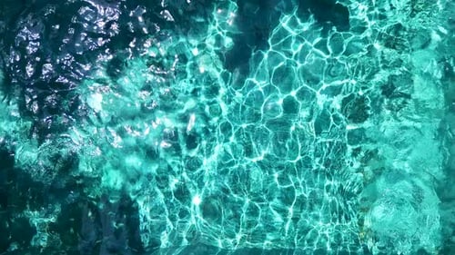 Aufnahme von einer Drohne aus blauem Wasser in einem Außenpool mit Lichtreflexen