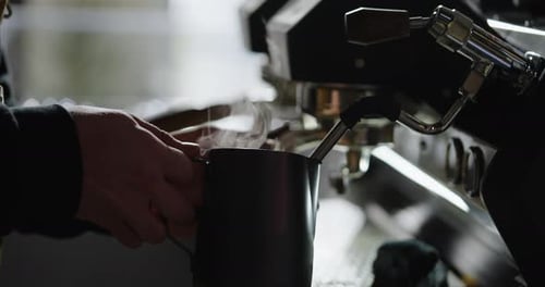 Hands Preparing Espresso with Steaming Milk