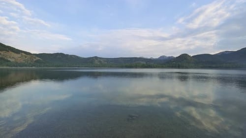 Beautiful clear lake surrounded by mountains. Summer scenery on a sunny day. Clear water with a r