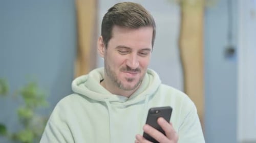Man Celebrates Good News on His Smartphone