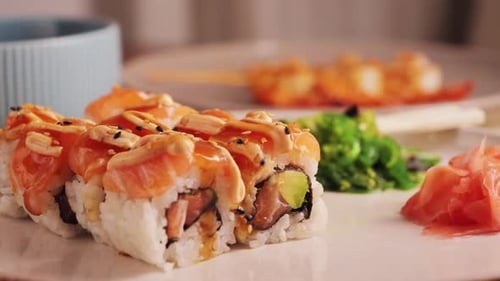 Appetizing sushi rolls with salmon, avocado with special sauce close-up on the table with ginger.