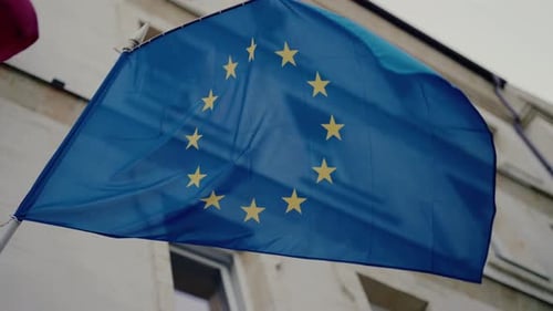 Waving European Union Flag Near Building on Overcast Day