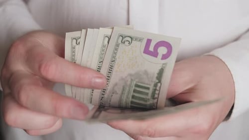 Contando dinheiro de perto com notas de cinco dólares em um contexto financeiro