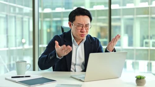 Concerned Businessman Reacts to Document on Laptop in Office