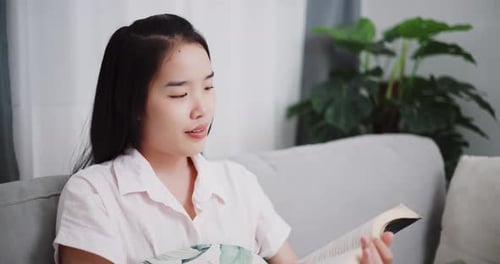 Young Woman Reading a Book on the Sofa