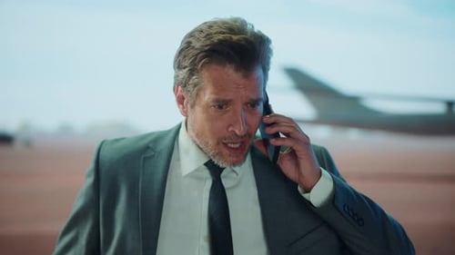 Businessman Talking Angrily on Phone at Airport