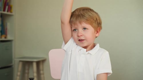 Boy with Blond Hair Raises Hand in Classroom