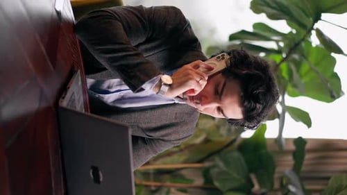 vertical video a serious man a businessman works at a laptop in the office communicates colleagues