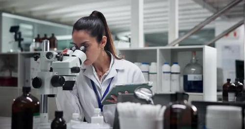 Female Scientist Looks Through Microscope in Lab