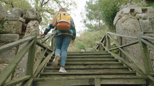 Woman Hiker Climbs Wooden Stairs at Historic Site