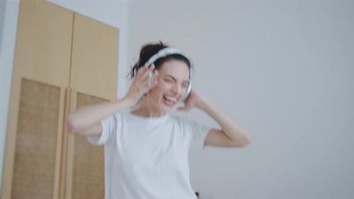 Woman Dancing Enthusiastically on Bed with Headphones On