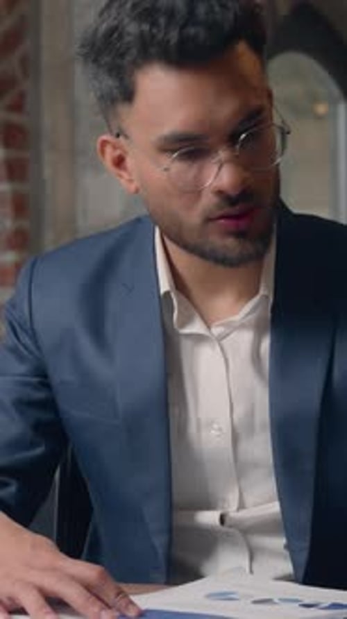 Focused Man Reviews Graphs in Office Attire