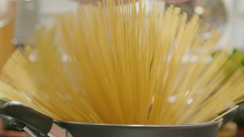 Hands of Man Cooking Spaghetti in a Pot