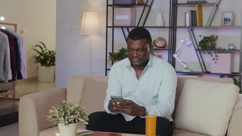 Man Using Smartphone While Relaxing on Sofa at Home