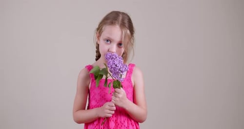 Girl Holding Lilac Flowers to Face in Studio