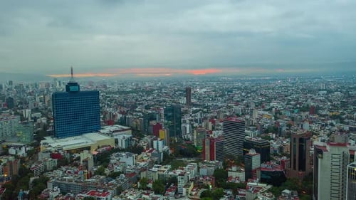 Aerial moving time lapse view of overcast clouds moving over the city, revealing a colorful sunrise