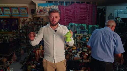 Un homme dans le quartier des friperies de Tunis tient deux lampes Aladdin.