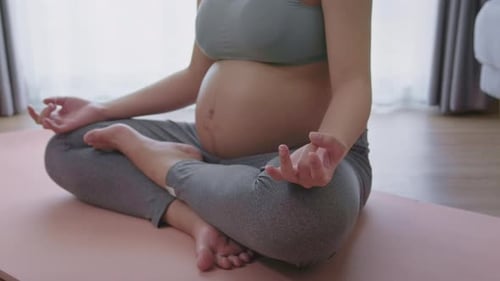 Pregnant Woman Meditating in Yoga Pose Indoors