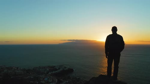 Silhouette of Hiker Man Standing on Mountain Top at Sunset