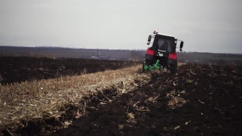 Red tractor plowing the field in Ukraine
