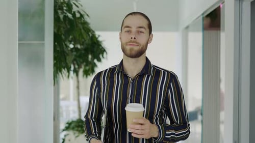 Man Walking in Office Hallway with Coffee