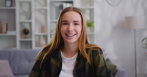 Retrato de niña encantadora sonriendo mirando a la cámara en casa. Joven rubia sonriente