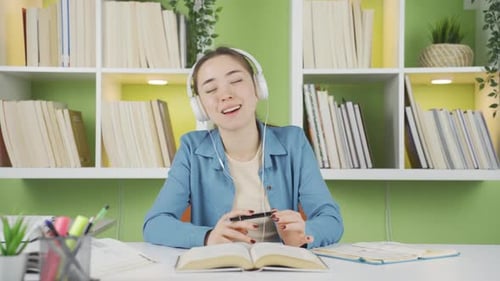 Smiling Young Woman Listening to Music While Studying