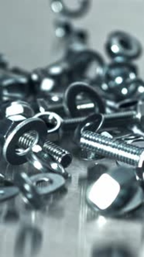 Industrieszene mit verschiedenen Muttern, Schrauben und reflektierenden Oberflächen, gefilmt mit einer Hochgeschwindigkeitskamera bei