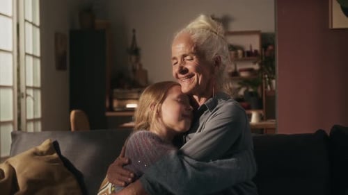 Senior Woman Hugging Girl on Couch