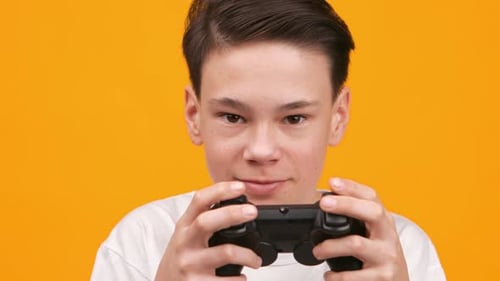 Young Person Playing Video Games With a Controller Against a Bright Yellow Background in Footage