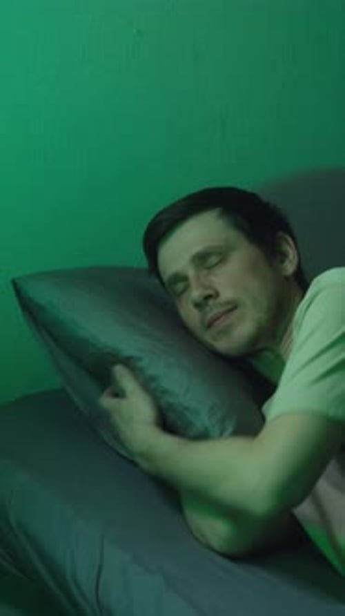 Young Man Going to Sleep in a Dark Green Room