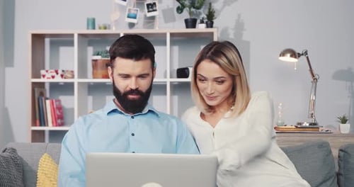 Couple using laptop computer together on sofa