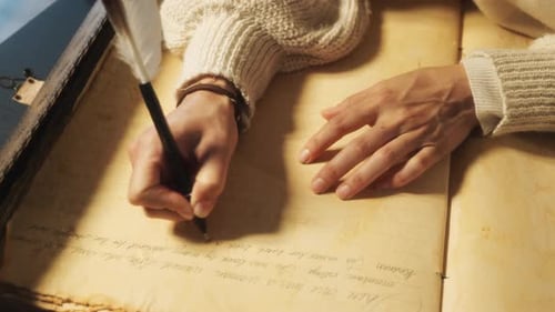 Detailed shot of a hand writing in cursive with a feather quill. A nostalgic and artistic scene