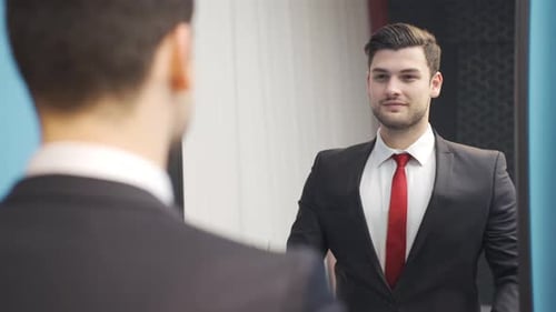 Confident Man Adjusting Suit in Mirror Indoors