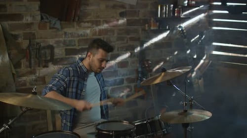 Drummer plays music while rehearsing a song in a home studio in a garage.