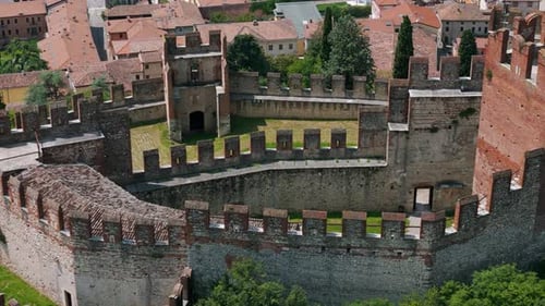 Aerial view of ancient castle walls, featuring a green courtyard and surrounding buildings, showcasi