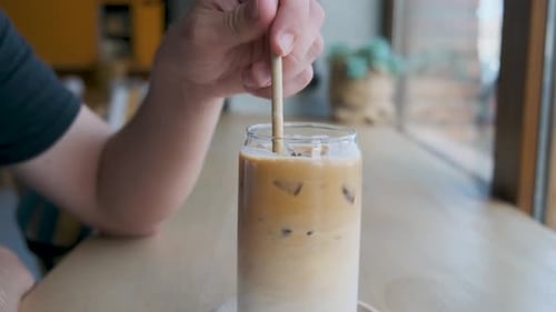 Man Drinking Iced Latte Coffee in a Glass with a Straw in Coffee Shop Cold Summer Refreshment Drink