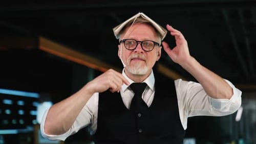 Un homme caucasien adulte portant des lunettes tient un livre sur sa tête. Un homme mûr s'amuse au bureau
.