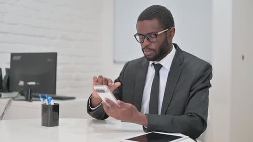 Man In Suit Using Cellphone At Office Desk