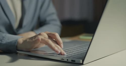 Closeup of Female Hands Working with Laptop Typing at Desk in Office in Evening