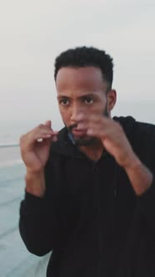 Young athlete boxer practicing punching technique while standing on the embankment