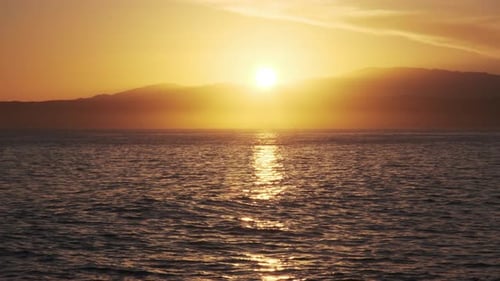 Breathtaking sunset illuminates the horizon, casting a golden glow over the ocean with distant