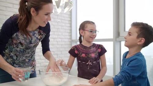 Familia cocinera Diviértete en la cocina. Madre cocinando con niños. Mujer joven cocinando pastel con niño...